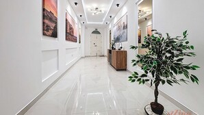 Een hal met een gepolijste vloer, kunstwerken aan de muur, inbouwverlichting en een potplant.