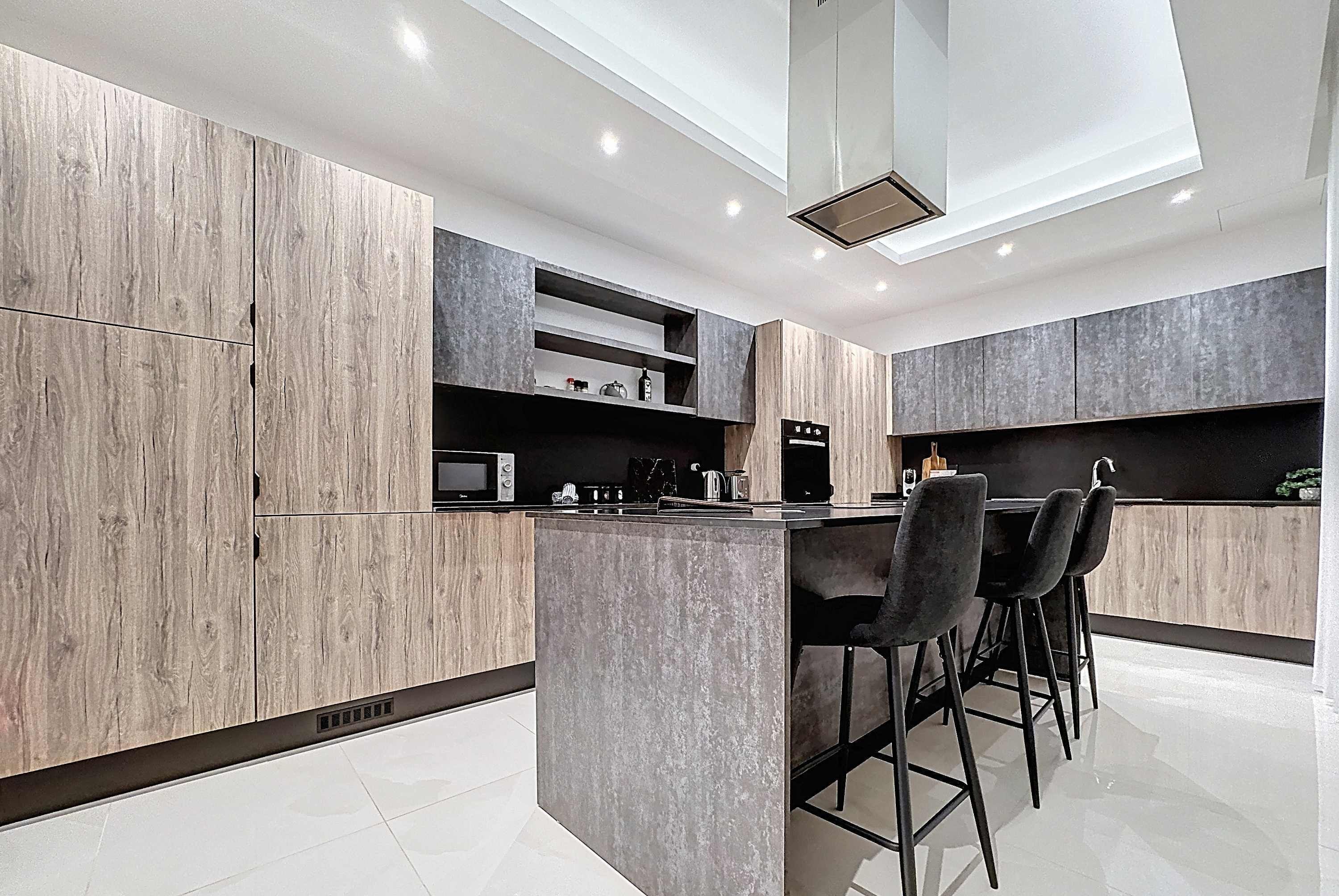 Una cocina moderna con una isla central, taburetes de bar y electrodomésticos integrados.