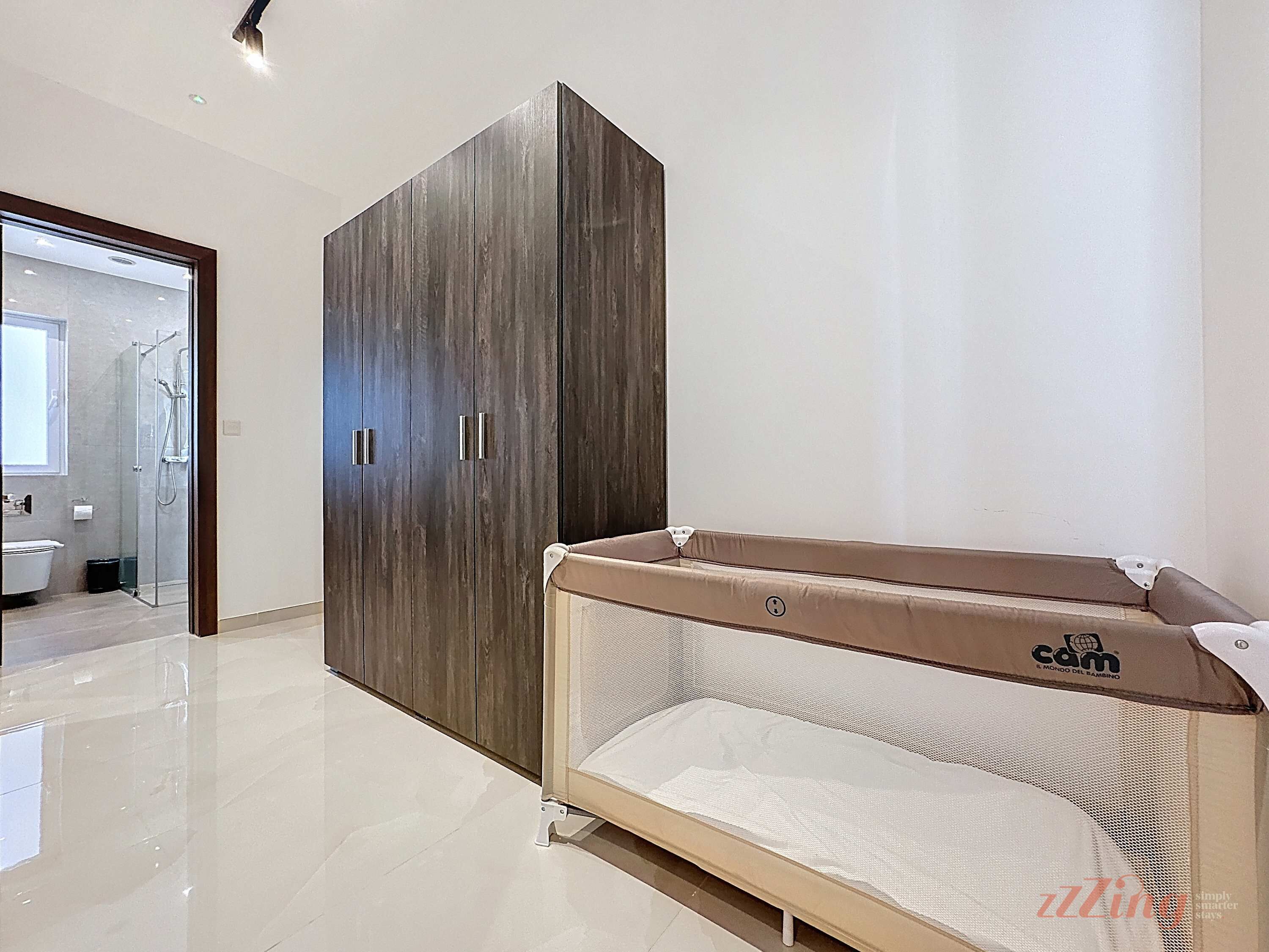 A modern bathroom with a glass shower enclosure, a wooden wardrobe, and a baby changing station.