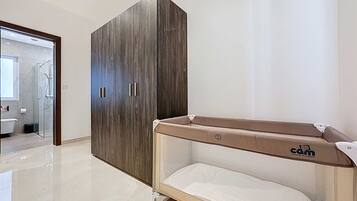 A modern bathroom with a glass shower enclosure, a wooden wardrobe, and a baby changing station.