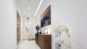 A hallway with a wooden cabinet, a potted plant, and a framed picture on the wall. - Rooftop Villa w/ Pvt Plunge Pool & BBQ in South (Ħal Għaxaq)