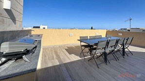 A rooftop terrace with a table and chairs, a sink, and a view of the city skyline. - Rooftop Villa w/ Pvt Plunge Pool & BBQ in South (Ħal Għaxaq)