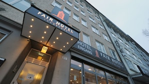 Das äußere Erscheinungsbild des Fair Hotel Frankfurt, mit einer modernen Fassade, großen Fenstern und einem markanten Eingang.