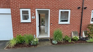 A red brick building with two windows and a door, number 18. - Modern 3-Bedroom Home in Bletchley, Milton Keynes (Bletchley)