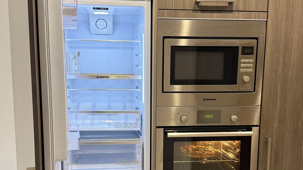 A kitchen with a built-in refrigerator, microwave, and oven. - Modern 3-Bedroom Home in Bletchley, Milton Keynes (Bletchley)