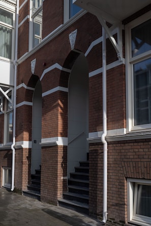 A multi-story building with brick walls, white trim, and a series of steps leading to an entrance. - Hotel Zest Den Haag - Scheveningen (The Hague)