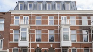 A multi-story building with a brick facade, multiple windows, and a flat roof. - Hotel Zest Den Haag - Scheveningen (The Hague)