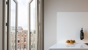A modern kitchen with a view of a cityscape through a glass door. - Hotel Zest Den Haag - Scheveningen (The Hague)