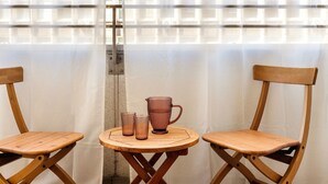 A room with two wooden chairs and a small round table, a window with a grid pattern, and a curtain. - Quiet and well decorated apartment, city heart, Świętokrzyska (Kraków)
