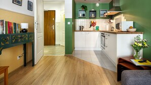 A modern kitchen with white cabinets, a green accent wall, and a wooden dining table. - Quiet and well decorated apartment, city heart, Świętokrzyska (Kraków)