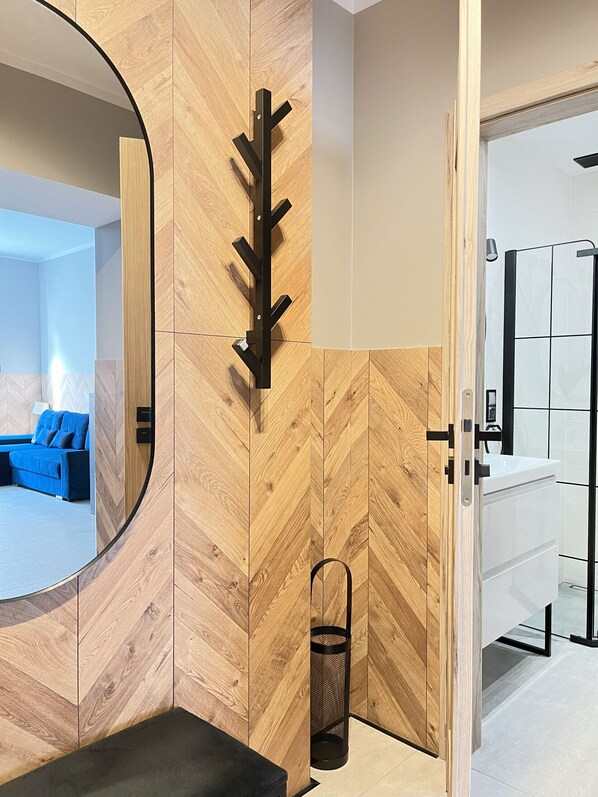 Une salle de bain moderne avec un mur en bois disposé en motif chevron, un porte-serviettes noir et une poubelle noire.
