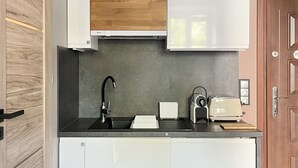 Eine kleine Küche mit weißen Schränken, einer Holz-Spritzschutzleiste, einem schwarzen Wasserhahn und einem Toaster.
