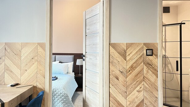 Ein Hotelzimmer mit Bett, Nachttisch, Stuhl und einer Duschkabine.