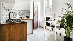 Une cuisine moderne dotée d’une cuisinière à gaz, d’un plan de travail recouvert de carreaux blancs et d’un coin repas avec une table et des chaises blanches.