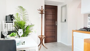 Une cuisine moderne avec des meubles blancs, une porte en bois et un coin repas comprenant une table et des chaises blanches.