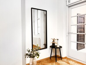 A corner room with a large mirror, a small table with a vase and a lamp, and a wooden herringbone floor. - Cozy Apartment for family next to Wawel II, Gertrudy 19 (Kraków)