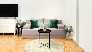 Una sala de estar con sofá, televisor, una mesita y alfombra redonda.