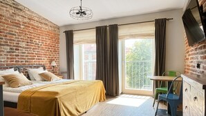 Un dormitorio con cama, escritorio, silla, cómoda y televisor montado en la pared.