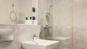 Un baño moderno con lavamanos, espejo y ducha.