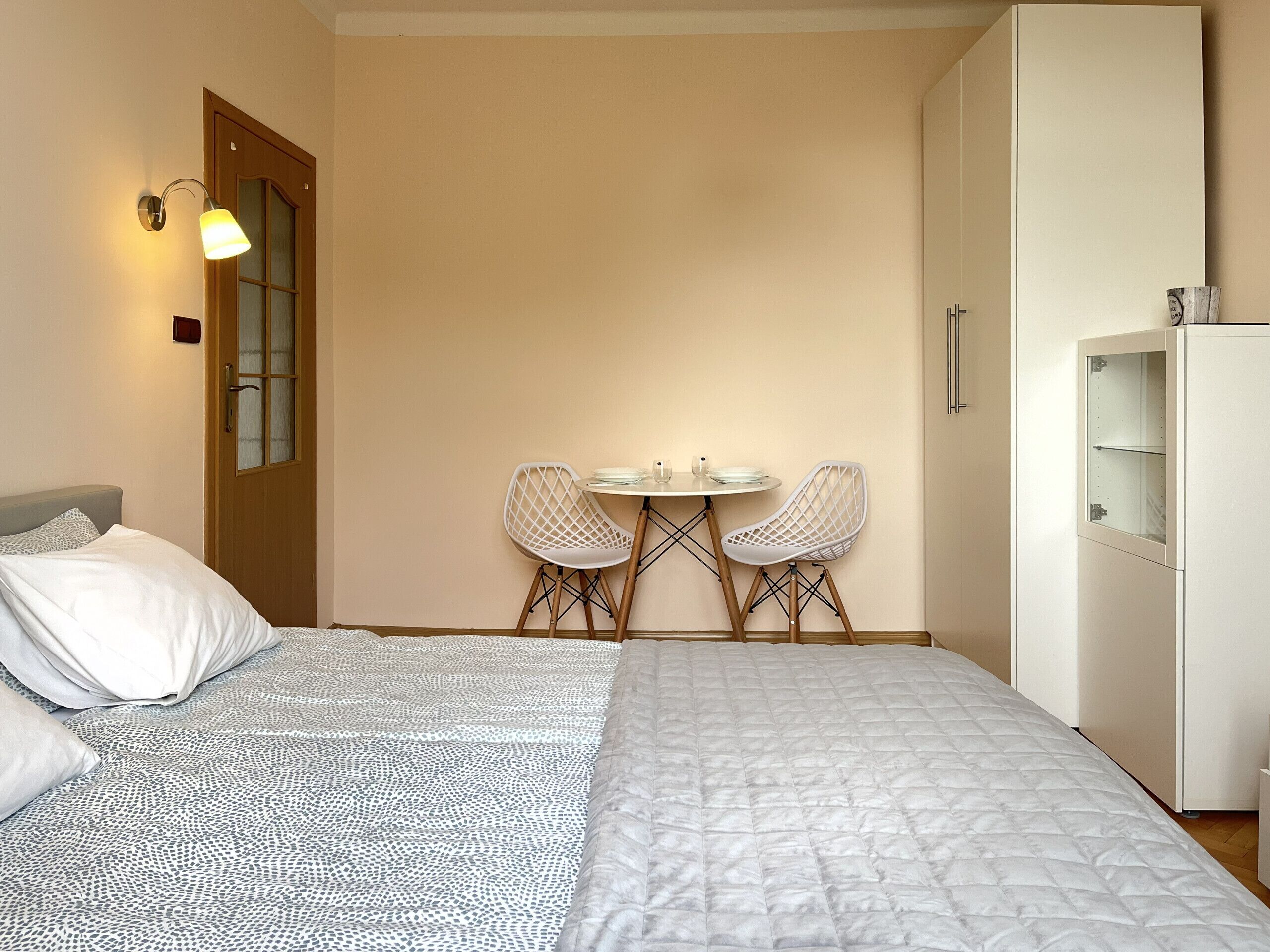 Een slaapkamer met een bed, een kledingkast en een eettafel met twee stoelen.