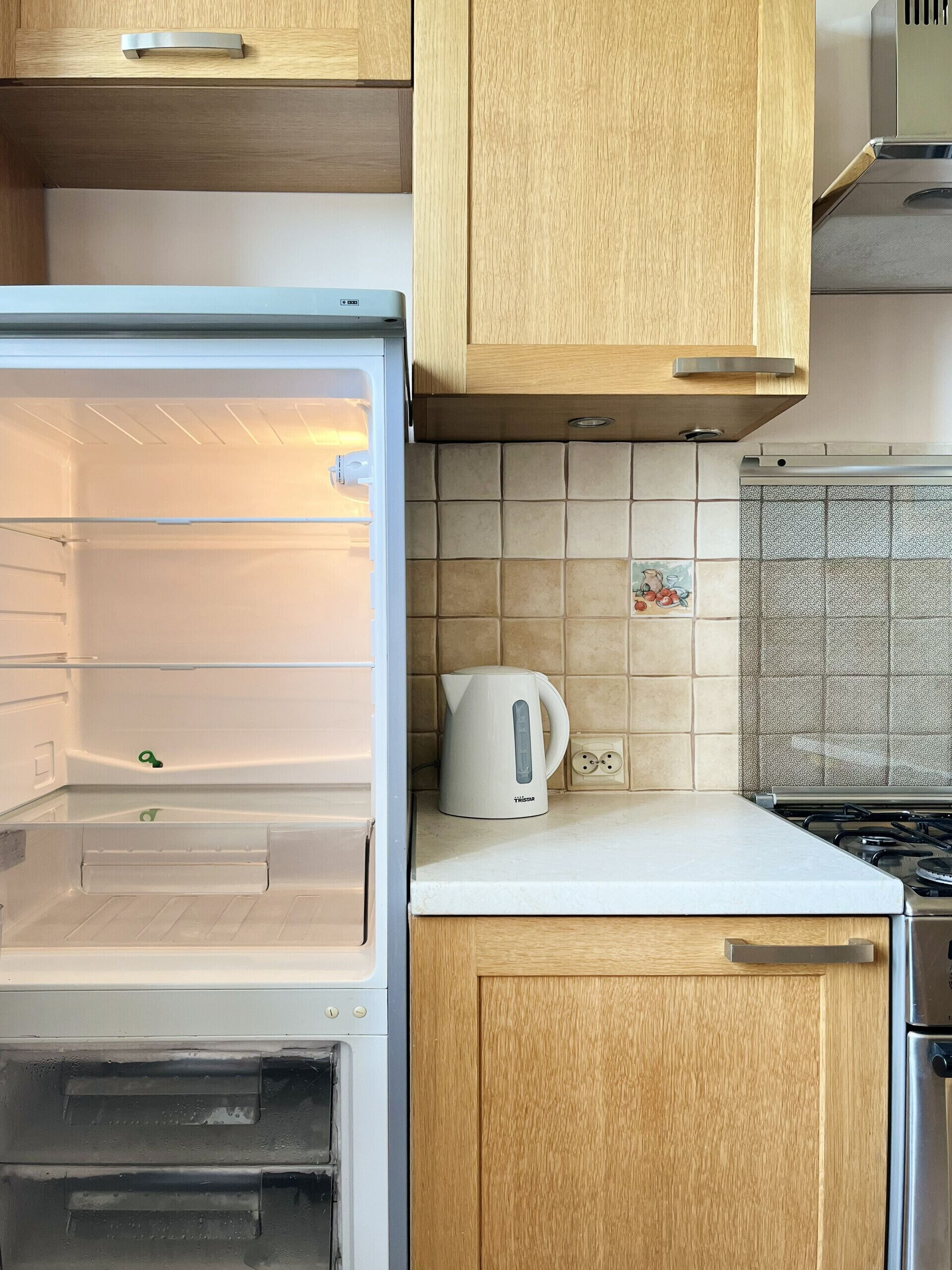 Una cocina con refrigerador empotrado, hervidor sobre la encimera y armarios de madera.