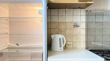 Una cocina con refrigerador empotrado, hervidor sobre la encimera y armarios de madera.