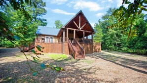 Eine Holzjagdhaus mit Veranda und Treppe, umgeben von Bäumen.