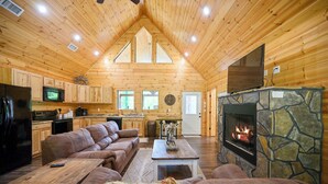 Ein Holzblockhaus-Interieur mit Wohnzimmer, Küche und Kamin.