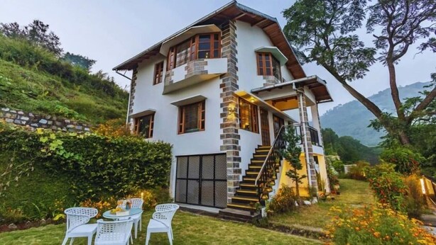 Una casa de dos plantas con fachada de piedra, un balcón y una escalera que lleva al piso superior.