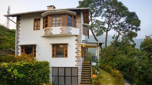Una casa de dos pisos con fachada de piedra, ventanas grandes y una escalera que lleva al piso superior.