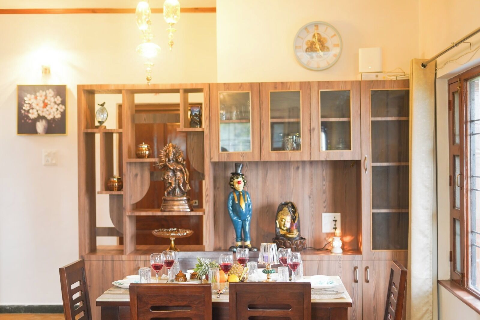A dining area with wooden cabinets, a clock, and a Buddha statue.