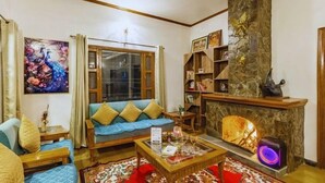 Una sala de estar con sofá, mesa de centro, chimenea y un cuadro de pavos reales.