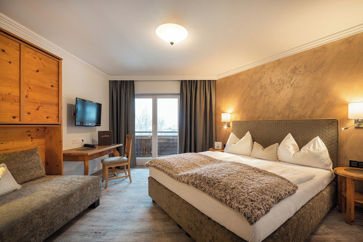 Une chambre d’hôtel avec un grand lit, un bureau, une télévision et une vue sur l’extérieur.