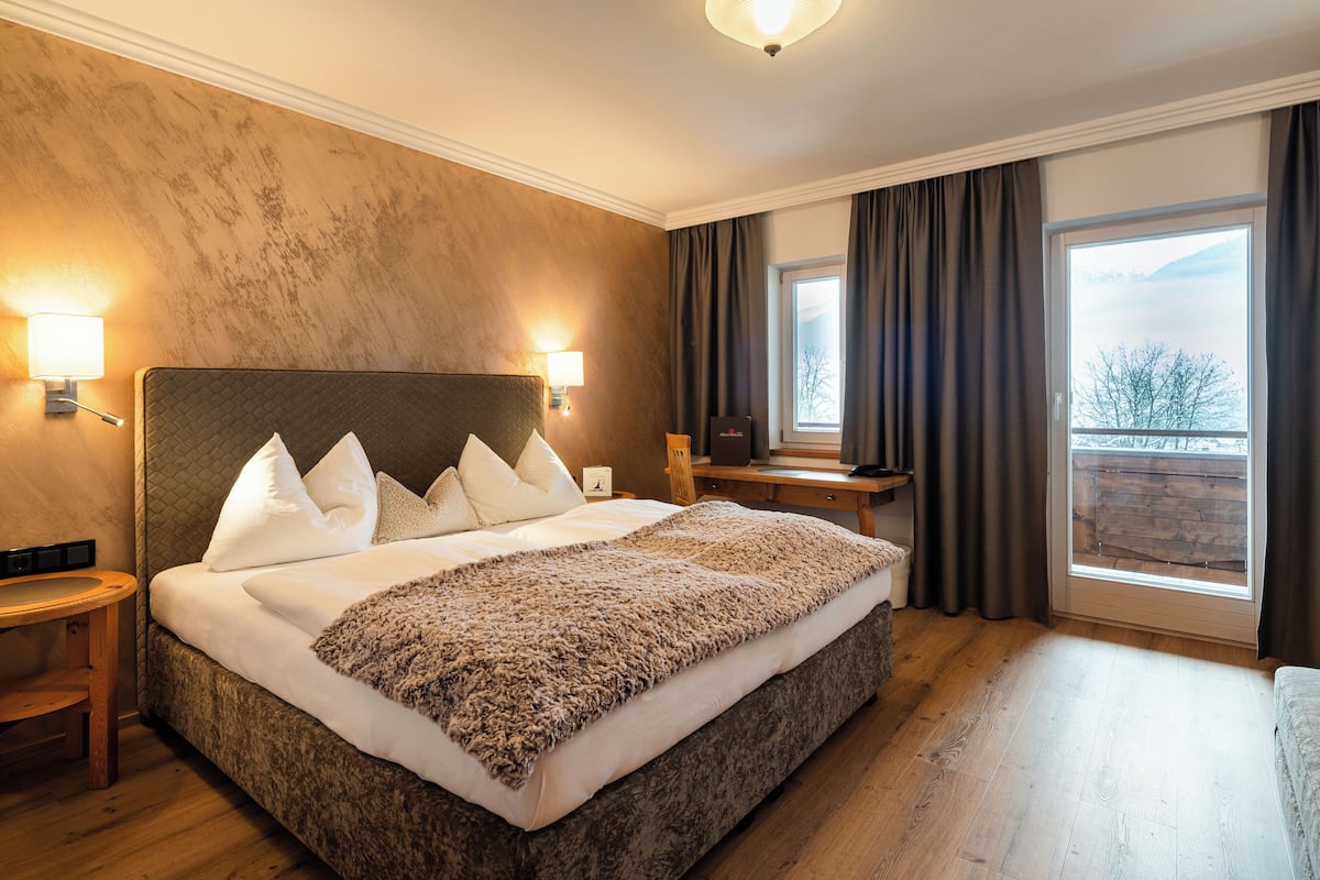 Une chambre d’hôtel avec un grand lit, deux lampes de chevet, un bureau et une vue sur l’extérieur.