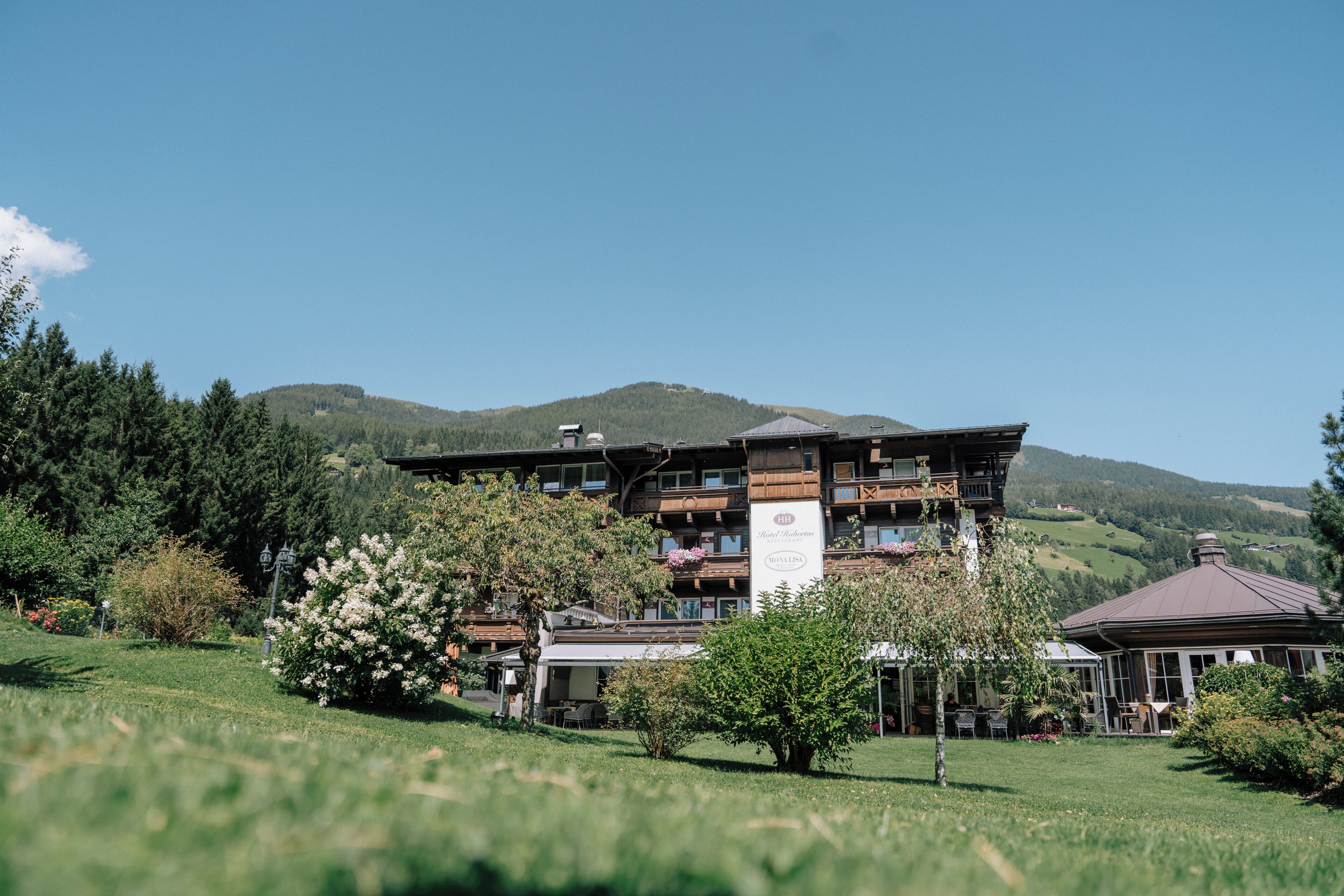 Ein mehrstöckiges Hotel mit Balkonen, umgeben von üppiger Vegetation und Bergen im Hintergrund.
