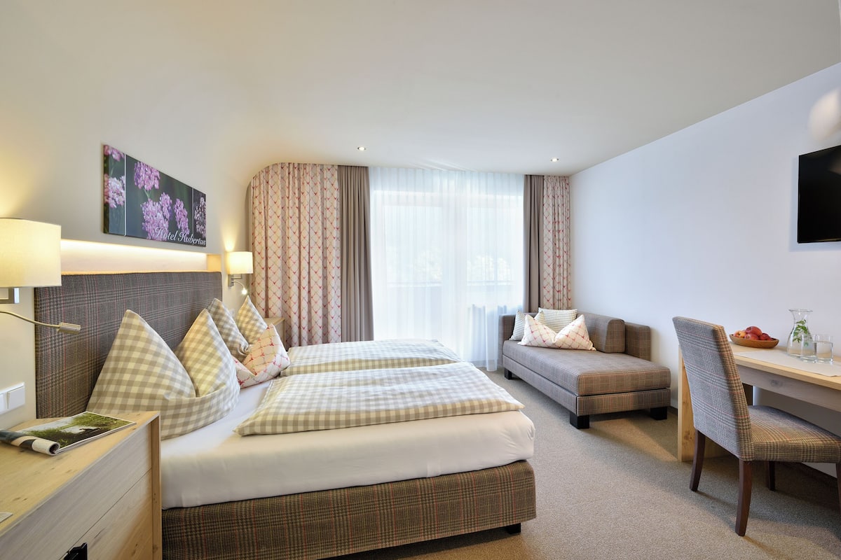 Une chambre d’hôtel avec deux lits, un bureau, une chaise et un téléviseur.