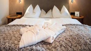 Un lit bien fait, recouvert d’une couverture moelleuse, une tête de lit ornée d’un motif matelassé, deux lampes de chevet et une petite table de chevet sur laquelle repose un livre.