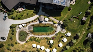 Vue aérienne d’un espace paysager comprenant un bassin central, des aires de repos aménagées tout autour et un bâtiment équipé de panneaux solaires.