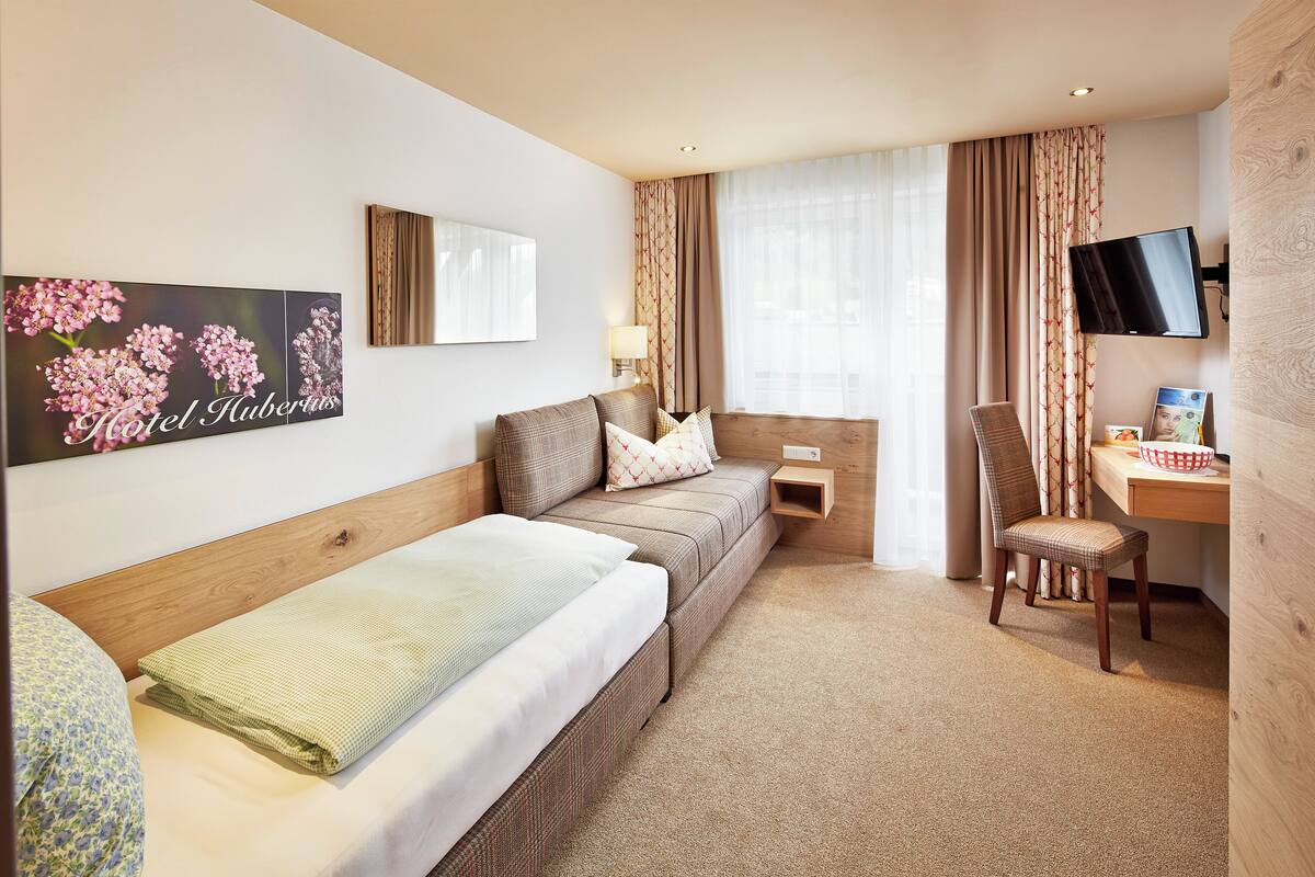 Une chambre d’hôtel avec un lit, un canapé, un bureau, une chaise, une télévision et un tableau au mur.