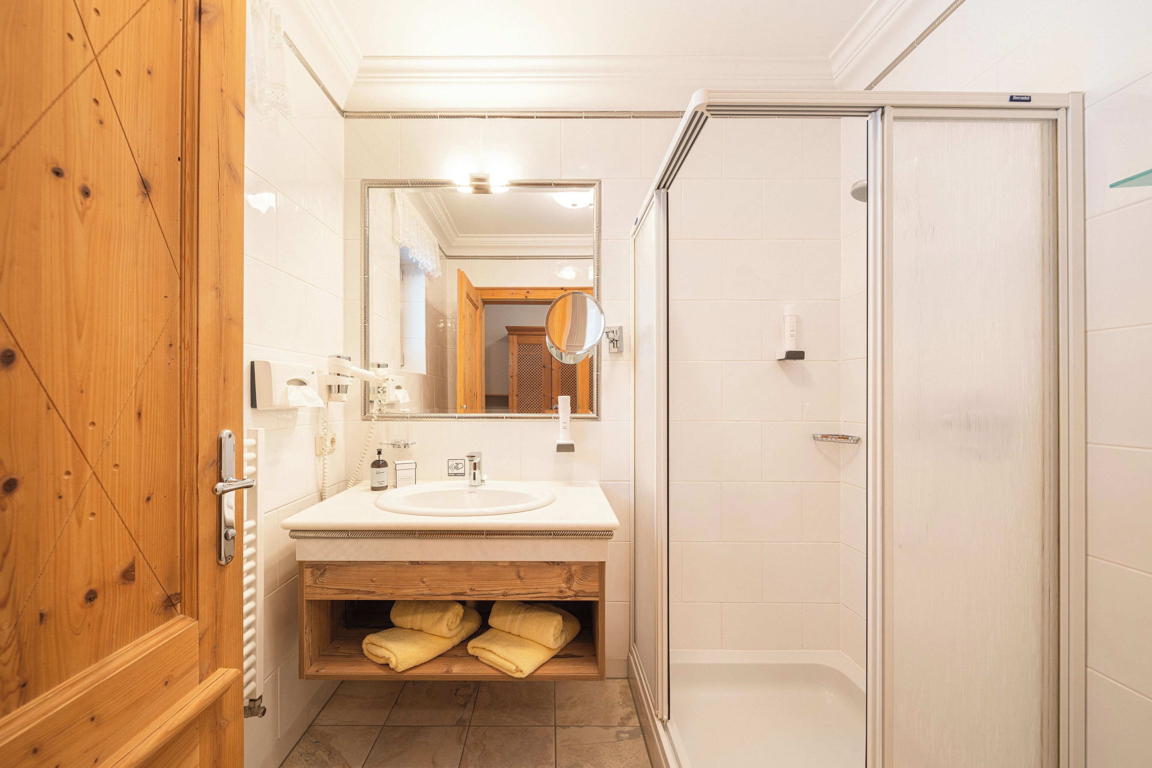 Une salle de bain avec un meuble-lavabo en bois, un évier, un miroir et un espace douche.