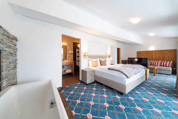 Una habitación de hotel moderna con una cama grande, televisor, cabecera de madera y una pared de acento de piedra.