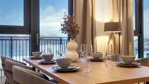 A dining table set with bowls and glasses, a vase with dried flowers, and a lamp. - EIR Three Bedroom Penthouse (Reykjavík)