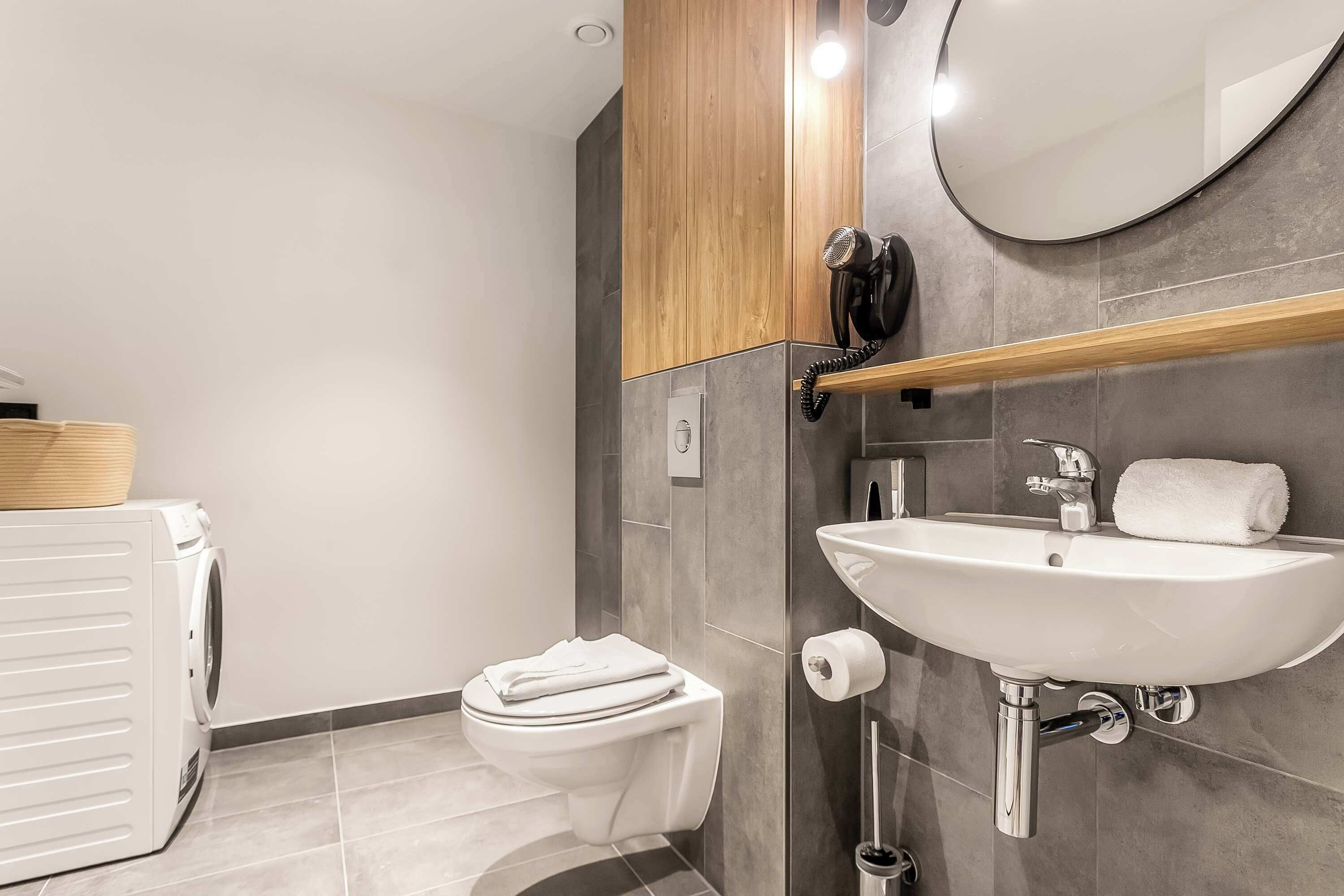 A modern bathroom with a toilet, sink, and a hairdryer on the wall.
