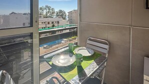 A balcony with a table, chairs, and a view of buildings and greenery. - Awesome apartment in Benalmadena (Benalmadena)