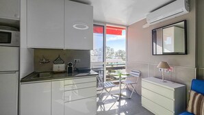 A compact kitchen with modern appliances, a dining area with a table and chairs, and a balcony with a view. - Awesome apartment in Benalmadena (Benalmadena)