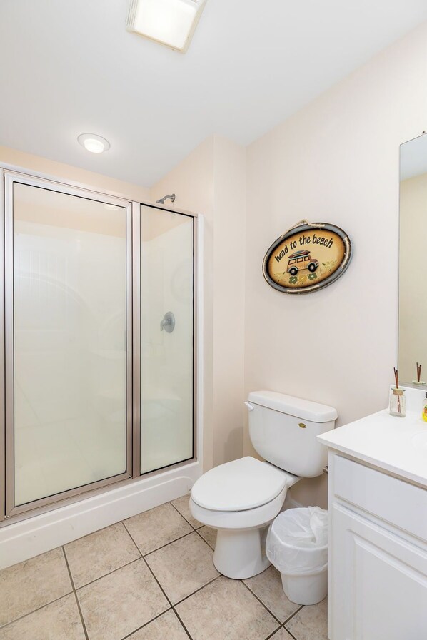 Une salle de bain avec une douche à parois de verre, des toilettes et un lavabo avec un miroir.