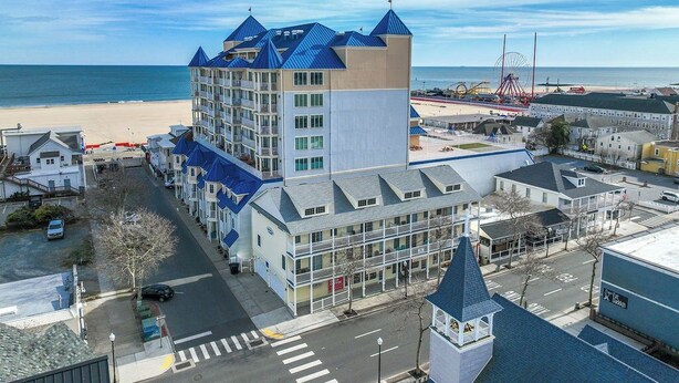 A coastal hotel with multiple floors, a prominent tower, and a beach view. - Cute, spacious 4-bedroom townhouse with free WiFi and easy access to shops located downtown on the ocean block! (Ocean City)