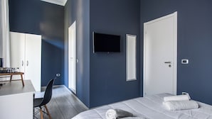 A modern hotel room with a large bed, a desk with a chair, a television, and a wardrobe. - Holiday Naples art room   (Naples)