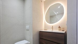 Een moderne badkamer met toilet, een wastafel met spiegel en een douchehoek.