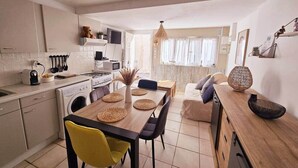 A modern kitchen with a dining area, a washing machine, and a sofa. - Loù Cabanoù 35 m from the seafront (Marseille)